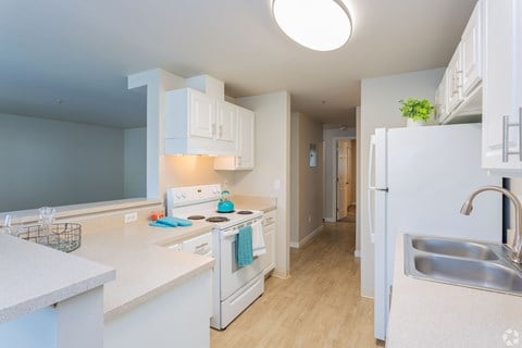 a kitchen with white cabinets and a stove and a refrigerator at Sitka Heights in Fife